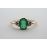 An emerald diamond ring, the oval cut em