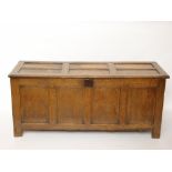 A late 17th/early 18th Century oak coffer, the six panel hinged lid over a four panel front,