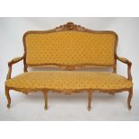 An early 20th Century French Louis XV style fruitwood settee, with moulded and leaf carved frame,