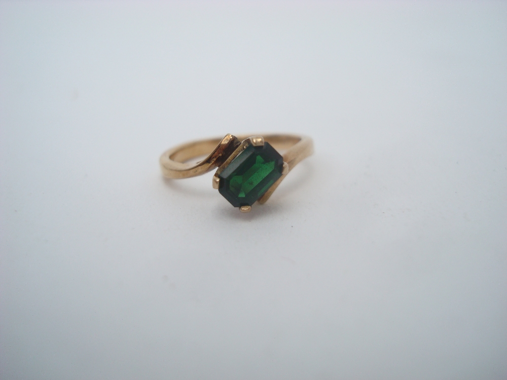 An emerald cross over ring, claw set stone, shank stamped 750, size L 1/2.