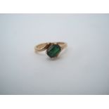 An emerald cross over ring, claw set stone, shank stamped 750, size L 1/2.