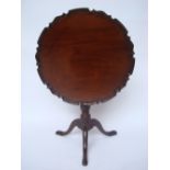 A George III style mahogany tripod table, the circular top with piecrust border and tilt action,