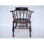 A late 19th Century elm beech smokers bow elbow chair, with spindle back above a solid elm seat,