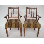 A pair of Indian teak elbow chairs, each with open arms and cane seats,