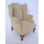 A late 19th/early 20th Century Queen Anne style upholstered wing armchair,