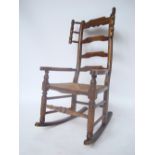 A late 19th Century beech ladderback rocking chair, with shaped arms and rush seat,