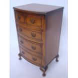 A reproduction walnut bowfront small chest of drawers, on squat cabriole legs.
