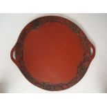 An early 20th Century twin handled Chinese red lacquer tray carved with foliate border.