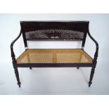 An Anglo Indian style ebonised hardwood settee, with cane seat.