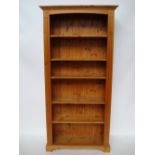 A modern pine open bookcase with adjustable shelves.