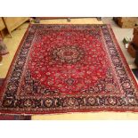 A large Persian meshed carpet, red ground field with central medallion within foliate borders.