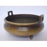 A Chinese bronze censer, of squat circular bellied form with uptight lug handles,