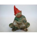 A Reconstituted stone garden gnome sat cross legged reading a book.