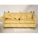 A modern Knole style two seated sofa with low back and sides on brass capped forelegs on casters,
