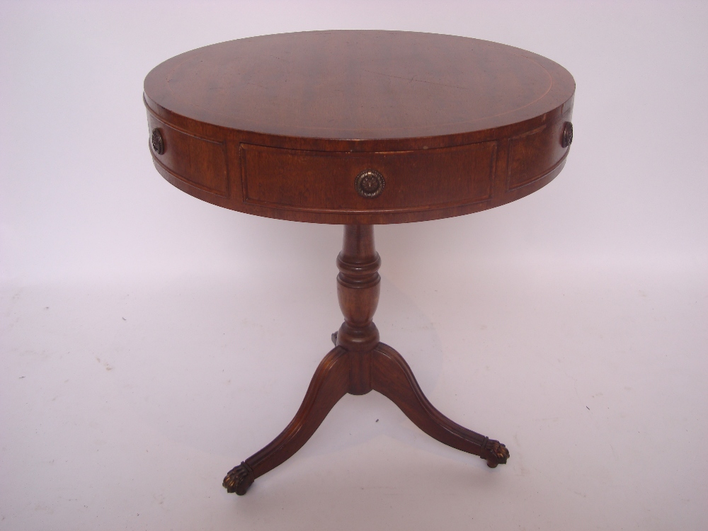 A reproduction mahogany low drum table on vase turned stem and tripod base with brass paw sabots.