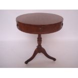 A reproduction mahogany low drum table on vase turned stem and tripod base with brass paw sabots.