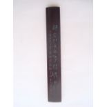 A Chinese hardwood scroll weight decorated with calligraphy.