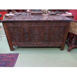 A heavily carved oak three panel coffer the hinged lid over stile feet, 76.5 x 136 x 56cm