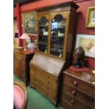 An Edwardian inlaid mahogany bookcase bureau, the two glazed doors over four long drawers on ogee