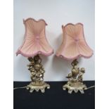 Two gilt figural lamps with urn, cherub and garland detail, shaped tasselled shades.  58cm tall