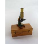 An early 20th Century compact brass monocular field microscope, adjustable tube, single lens,