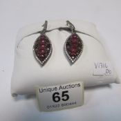 A pair of silver earrings set red and wh