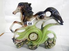 A Porcelain clock depicting horse jumping over clock face (approx. height 11 1/2" / 29.25 cm)