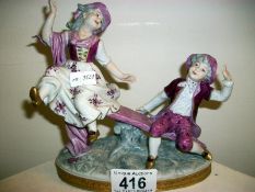 A Porcelain figure of boy and girl on see-saw