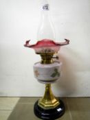 Victorian oil lamp with brass column, hand-painted vessel, and cranberry glass shade (approx.