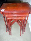 A Nest of four red lacquer tables with Oriental depictions (approx. height 25" / 63.5cm)