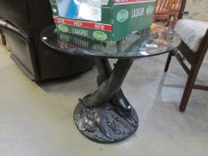 A glass topped occasional table supporte