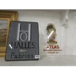 An Atlas Insurance company sign and a Halles Overseas Fabrics advertising sign