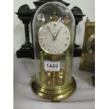 A brass anniversary clock under glass dome, in working order