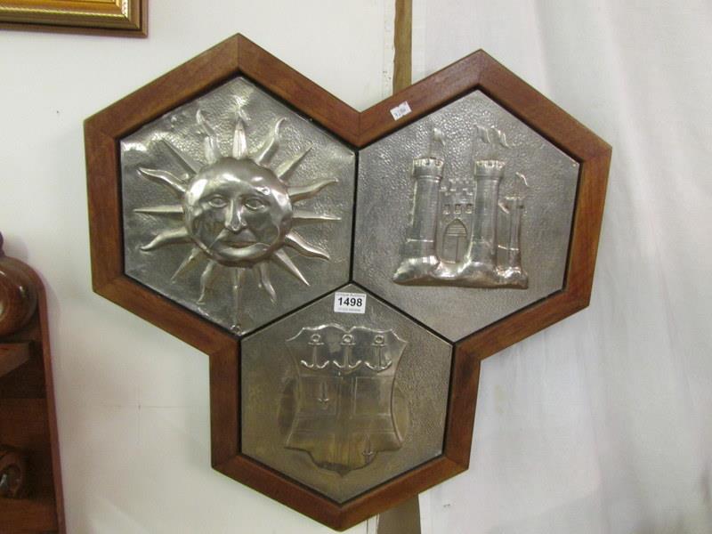 A pewter heraldic wall decoration on oak