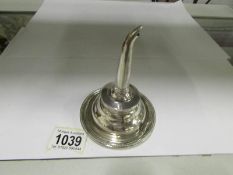 A silver wine funnel with strainer and t