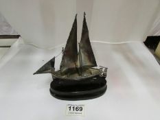 A silver model of a lifeboat under sail