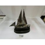 A silver model of a lifeboat under sail