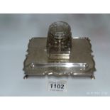 A silver inkstand with glass inkwell (in