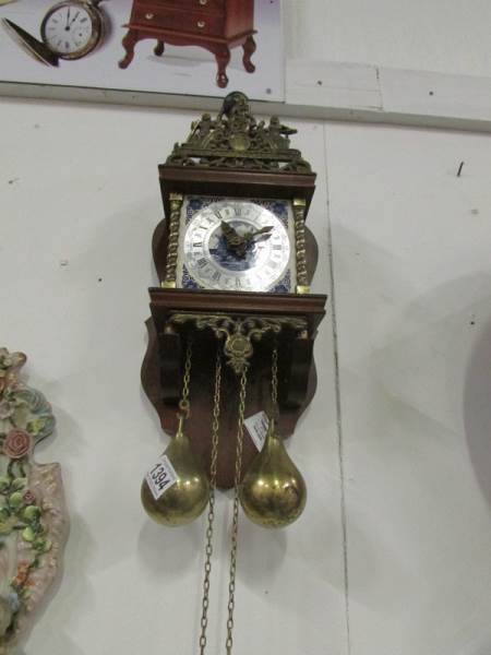 A wall clock with brass weights