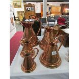 A set of 5 graduated copper jugs