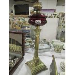 A brass Corinthian oil lamp with ruby gl