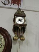 A brass faced wall clock with brass weig