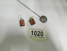 A silver hat pin and a pair of silver and tiger's eye earrings