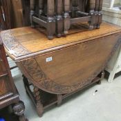 An early 20th century oak gate leg table with barley twist supports and carved frieze