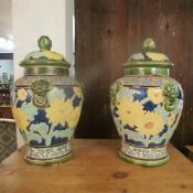 A pair of glazed terracotta lidded urns