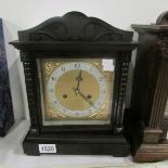 A black wood mantel clock with pendelum and key