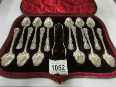 A cased set of 12 ornate silver spoons with sugar nips, Hall marked Sheffield 1899/1900,