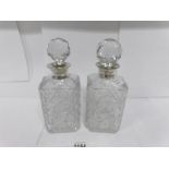 A pair of heavy cut glass decanters with silver collars