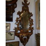 A gilt framed oval mirror with shelf