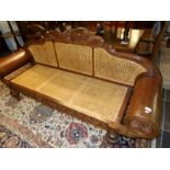 A carved settee with cane seat and back